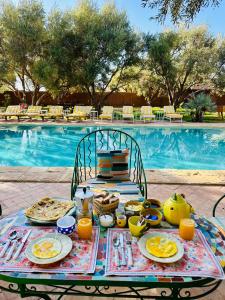 a picnic table with food on it next to a pool at Maison chaliya bohochic guesthouse in Marrakech +64 photos