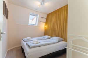 a small bedroom with a bed with blue sheets at Duinhof Klein Dishoek - Appartementen onder aan de duinen, in het centrum met terras in Dishoek