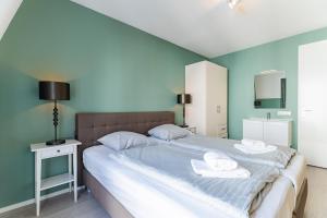 a bedroom with a large bed with towels on it at Duinhof Klein Dishoek - Appartementen onder aan de duinen, in het centrum met terras in Dishoek