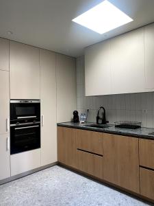 eine Küche mit weißen Schränken und einem schwarzen Backofen in der Unterkunft Misericórdia Garden Homes in Vila do Conde