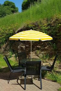 a table and chairs with a yellow and white umbrella at Ferienwohnung im Kasperhaus in Hohnstein