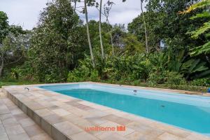 - une piscine dans une cour arborée dans l'établissement Kitnet em Aldeia Velha com piscina e churrasqueira, à Aldeia Velha