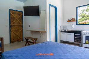 une chambre avec un lit et une cuisine avec une porte dans l'établissement Kitnet em Aldeia Velha com piscina e churrasqueira, à Aldeia Velha