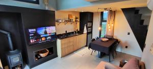 a living room with a television and a kitchen with a fireplace at Tiny House Cambará in Cambará