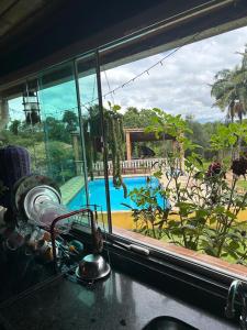 a kitchen window with a view of a swimming pool at Chácara São Marcos in Ibiúna