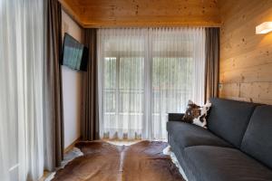 Una sala de estar con un sofá y una ventana grande. en Mayr Natur Apartments, en Santa Cristina Valgardena