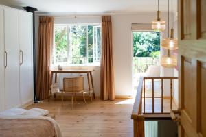 a bedroom with a desk and a table and a window at Sunset Stays Lavender Cottage in Cape Town +38 photos