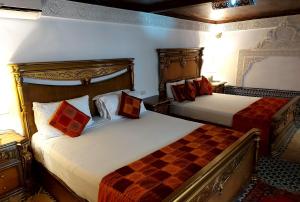 a hotel room with two beds with red pillows at Palais AL Firdaous in Fès +141 photos
