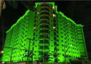 a green building with palm trees in front of it at Boulevard Suite in Caldas Novas +17 photos