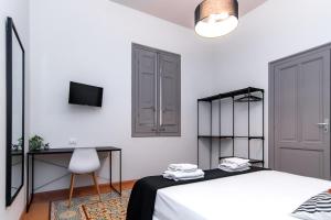 a white bedroom with a bed and a desk at Fardella Hospitality in Trapani