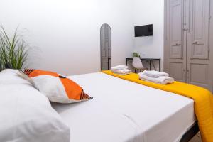 a bedroom with a white bed with orange and white pillows at Fardella Hospitality in Trapani