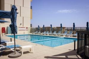 a swimming pool with lounge chairs and an umbrella at Marina Retreat Stylish One Bedroom by Hala Homes in Ras al Khaimah