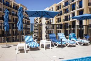 a group of chairs and umbrellas next to a pool at Marina Retreat Stylish One Bedroom by Hala Homes in Ras al Khaimah