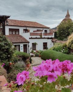 un jardín con flores rosas frente a una casa en Casona Del Duende, en Alájar