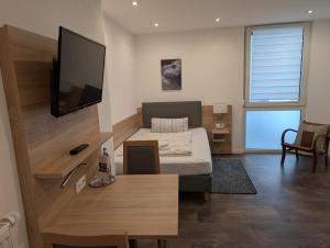 a bedroom with a bed and a flat screen tv at Pension zur Linde in Kleinwallstadt