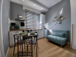 a small kitchen with a table and a blue couch at Litte Sweet Home - Abbiategrasso città in Abbiategrasso