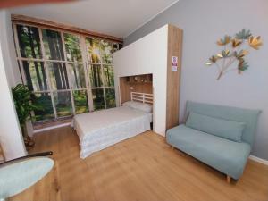 a small room with a bed and a couch and windows at Litte Sweet Home - Abbiategrasso città in Abbiategrasso