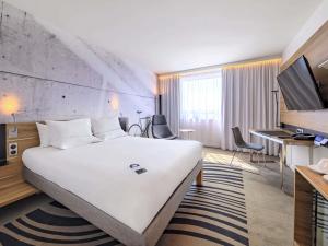 a hotel room with a large white bed and a desk at Novotel Kraków Centrum in Kraków