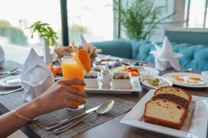 a person holding a glass of orange juice with a table of food at Best Western Plus Jeddah Hotel Madinah Road in Jeddah