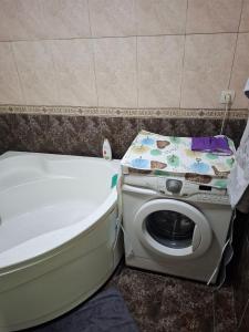 y baño con lavadora junto a la bañera. en Lucky Hostel oilaviy korxona, en Yakkasaray
