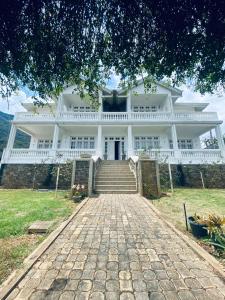a large white house with stairs in front of it at Seventh Heaven Villa in Hakgala