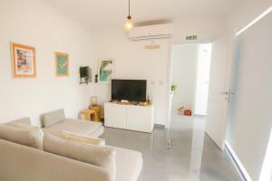 a white living room with a couch and a tv at Sunny Penthouse with Large Terrace in Marsaxlokk