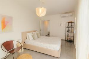 a white bedroom with a bed and a table at Sunny Penthouse with Large Terrace in Marsaxlokk