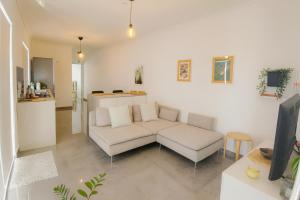 a living room with a white couch and a tv at Sunny Penthouse with Large Terrace in Marsaxlokk