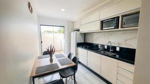 a kitchen with a table and chairs and a sink at Apto central ideal para casais e famílias em Foz 3 in Foz do Iguaçu