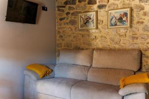 a couch in a living room with a stone wall at La Casita de Verdiago in Verdiago