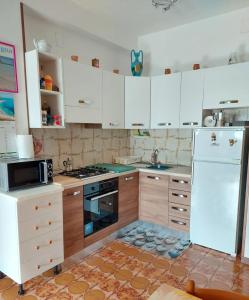 una cucina con mobili bianchi e un frigorifero bianco di AndEli ad Alghero