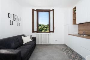 a living room with a black couch and a window at La casa nel verde di Francesco in Lipomo