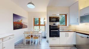 a kitchen with white cabinets and a table and a dining room at The Nest in Summerseat