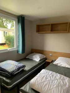two beds in a room with a window at Mobil home 4 personnes in Pont-Aven