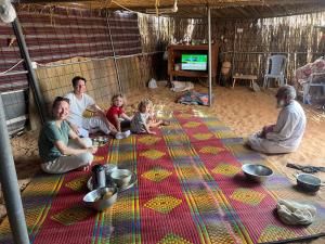 QābilにあるDream Desert Campの床に敷いた毛布の上に座っている人々のグループ