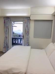 a bedroom with two white beds and a window at 九份巷居民宿 in Jiufen