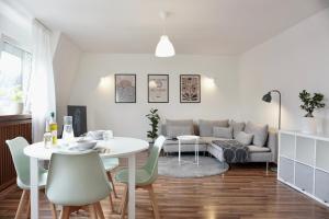 a living room with a table and a couch at NEU Gemütliche Wohnung für max 5 Personen mit Balkon nähe Mosel mit Blick auf die Weinberge in Koblenz