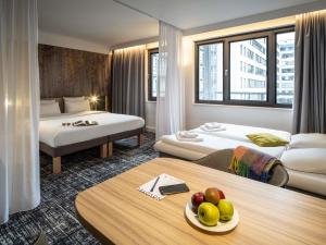 a hotel room with two beds and a table with fruit on it at Novotel Suites Wien City Donau in Vienna