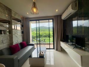 a living room with a couch and a large window at The Lago Nai Harn 2 BR-Walk to beach in Rawai Beach