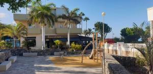a playground in front of a building with palm trees at La Caleta Seaside Villa With Pool in Adeje