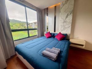 a bedroom with a blue bed with a large window at The Lago Nai Harn 2 BR-Walk to beach in Rawai Beach +16 photos