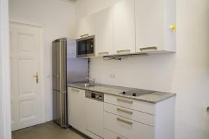 a kitchen with white cabinets and a stainless steel refrigerator at Schlossquadrat Apartment 17 in Vienna