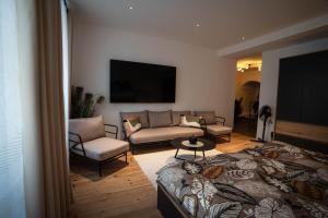 a bedroom with a bed and a couch and a tv at Laubennest 1 in Merano
