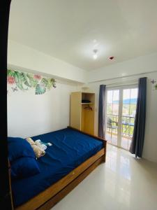 Un dormitorio con una cama con sábanas azules y una ventana. en 2-Bedroom Ladera Suites, en Baguio 3 fotos más