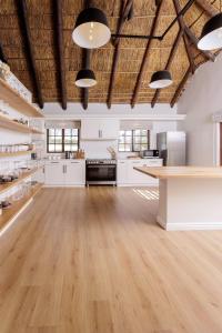 a large kitchen with white cabinets and a wooden floor at Villa Canetsfontein in Wellington +27 photos