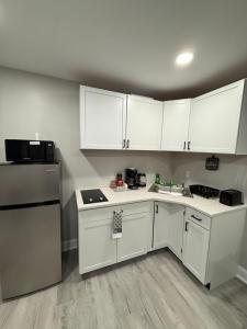 a small kitchen with white cabinets and a sink at New Cozy Private Studio JFK in Morris Park