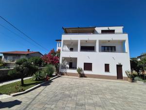 a white house with a driveway in front of it at Apartmani Nika in Rijeka