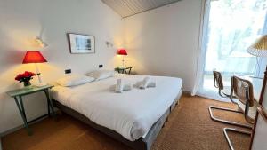 ein Schlafzimmer mit einem weißen Bett mit zwei Lampen und einem Fenster in der Unterkunft Jolie maison avec jardin, piscine et parking in Sainte-Marie-de-Ré