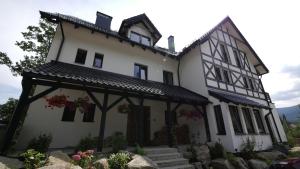 a white and black house with flowers in front of it at Willa Uroboros in Szklarska Poręba