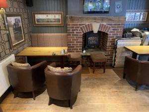 a restaurant with a brick fireplace and tables and chairs at George & Dragon in Tarvin